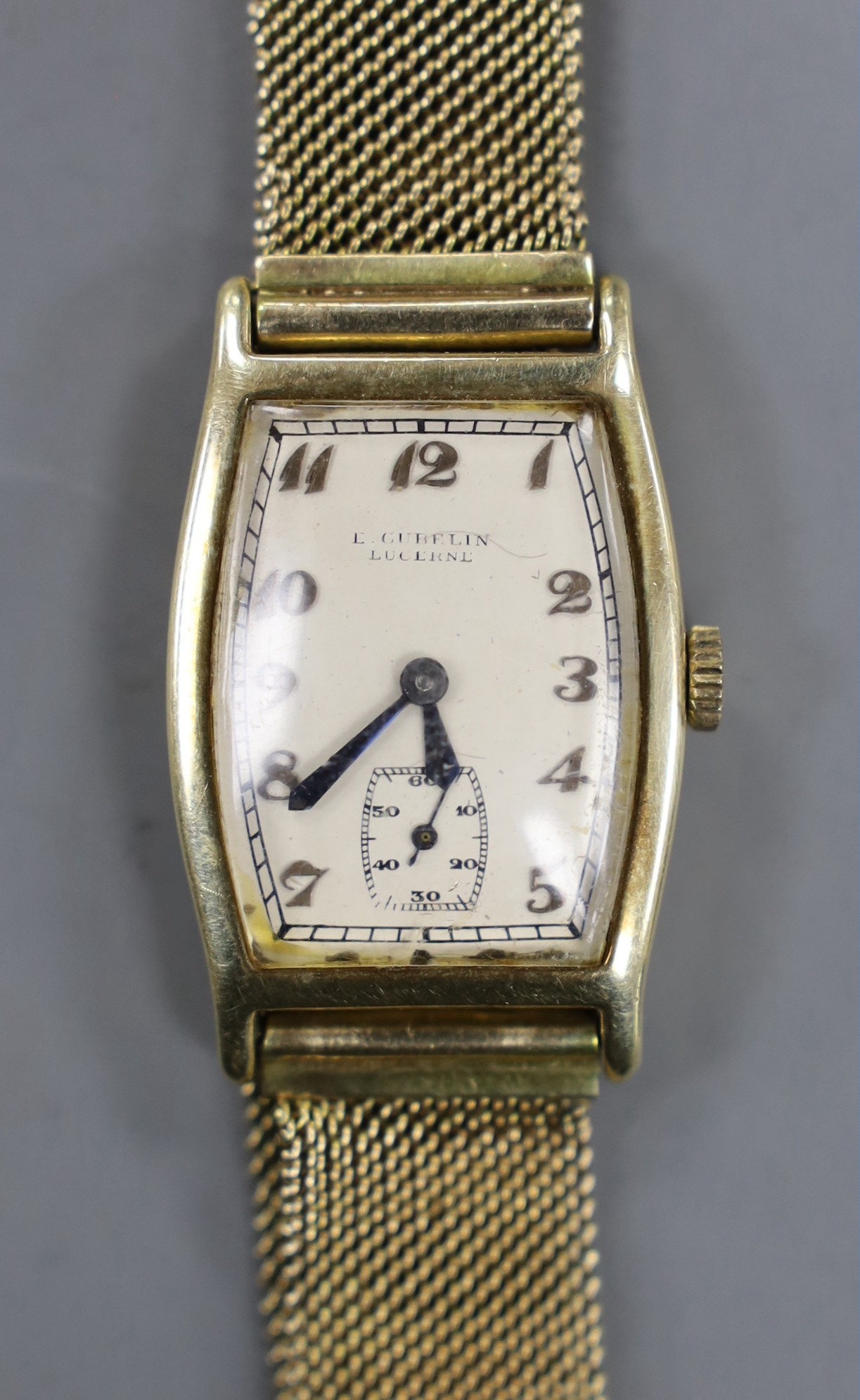 A gentleman's 14k tonneau shaped manual wind wrist watch, retailed by E. Cubelin, with Arabic dial and subsidiary seconds, on associated 9ct gold mesh link bracelet